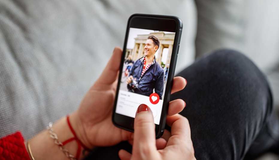 Close-up of a female using a dating app on smart phone. Woman looking at man on an online dating app on her mobile phone.