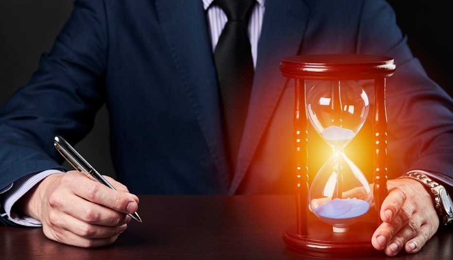 torso of a businessman holding a pen and an hourglass that is glowing red