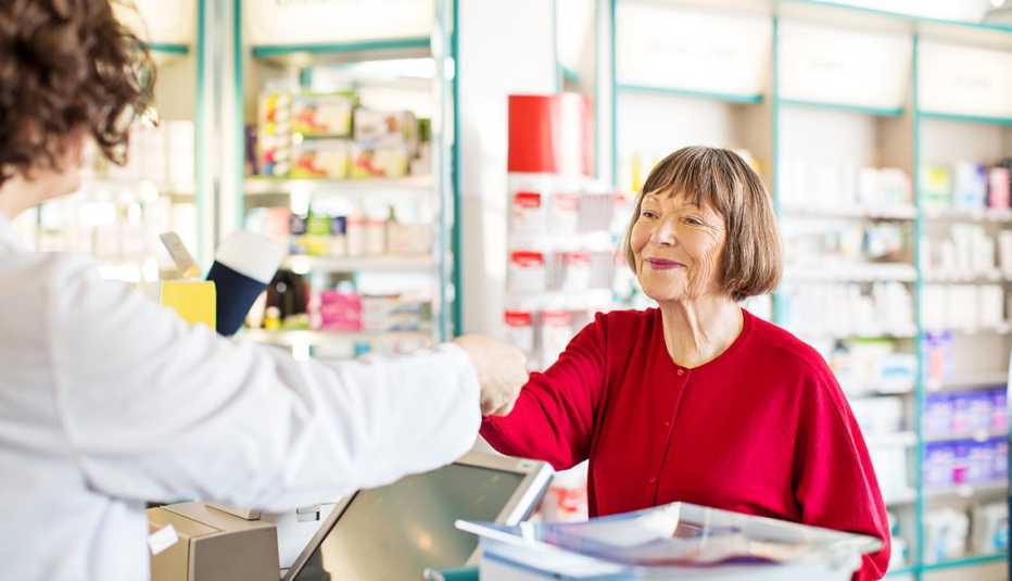 a woman handing her debit card to the pharmacist to pay for medication