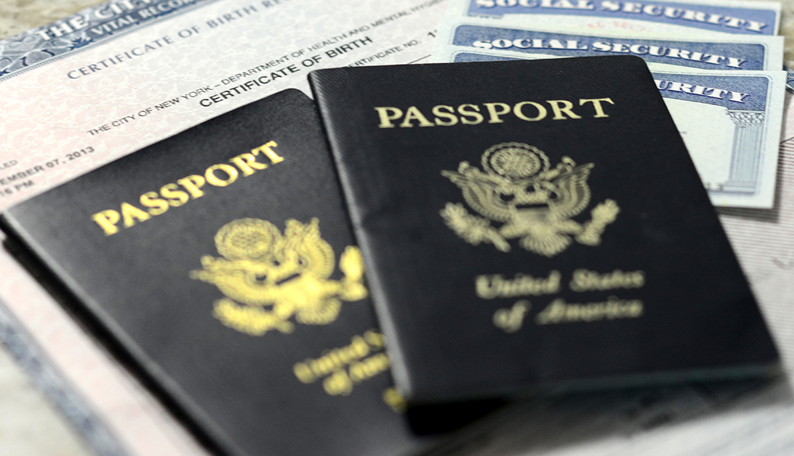 Different forms of identification. pictured are three social security cards on  top of a birth certificate covered by two american passports.