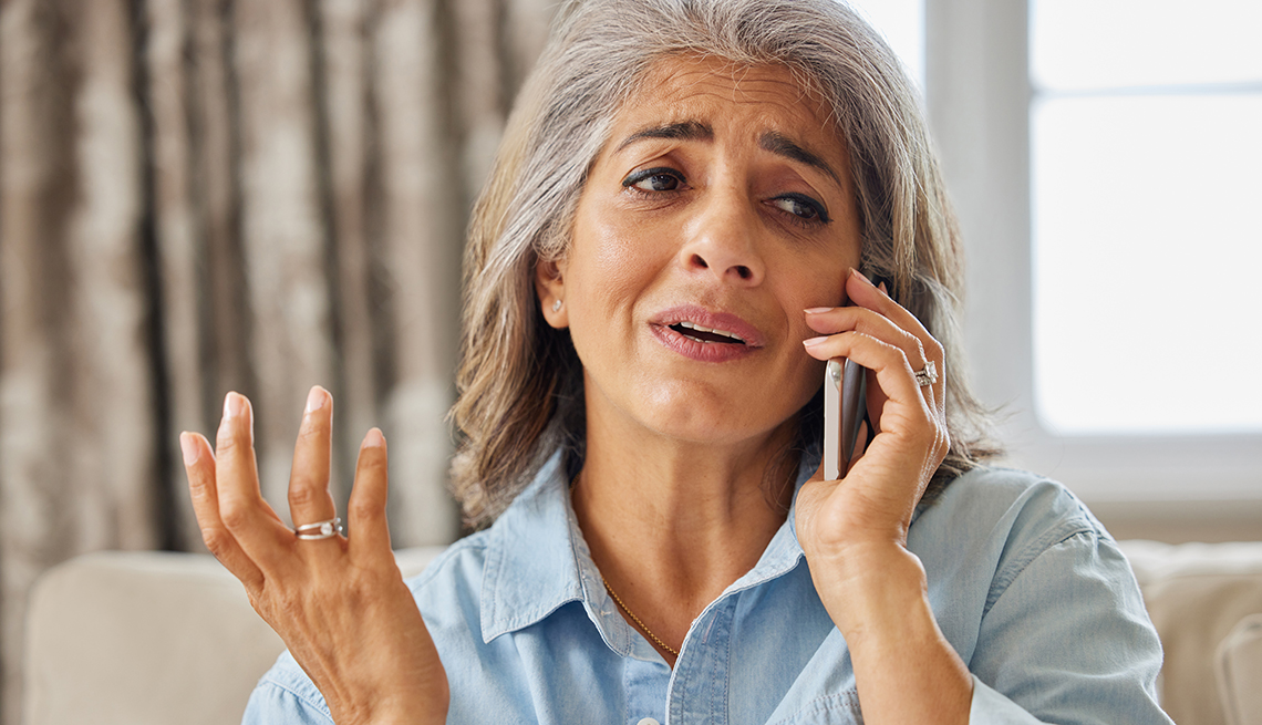 Frustrated woman receiving unwanted telephone call at home